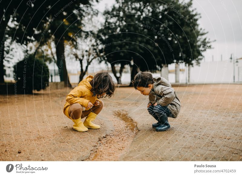 Brother and sister playing outdoors Rain rainy Brothers and sisters Child childhood 1 - 3 years 3 - 8 years Rubber boots Happiness Leisure and hobbies Playing