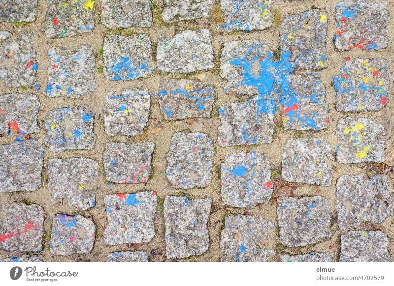 public nuisance I top view of gray pavement soiled with blue, red and yellow paint / damage to property Paving stone Colour plan Yellow Damage to property Red