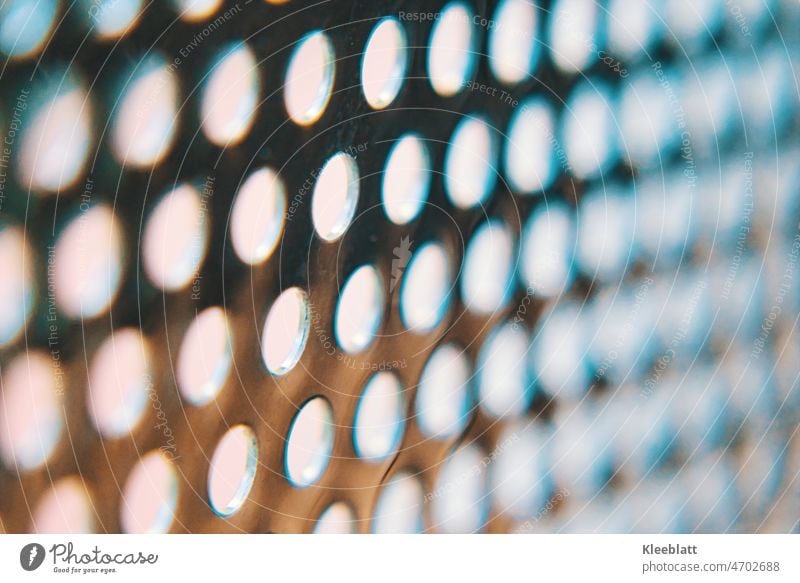 Stainless steel perforated sheet with light bluish background - partial blur High-grade steel Plate with holes Artistic bluish coloring blurriness hazy