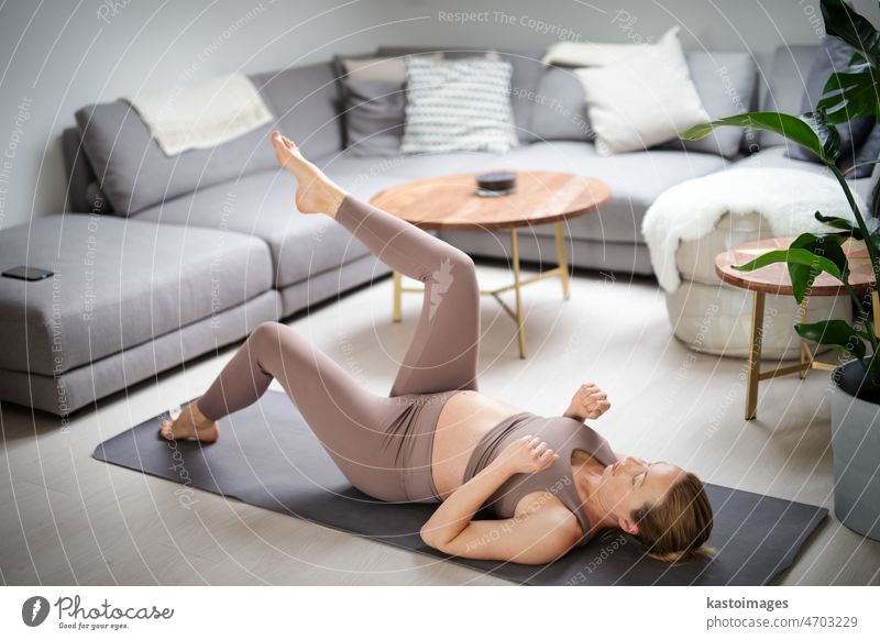 Young beautiful pregnant woman training pilates at home in her living room. Healthy lifestyle and active pregnancy and motherhood concept. yoga baby care