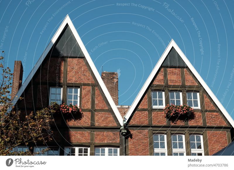 Old houses with half-timbering, brown brick and pointed gable in summer against blue sky in the sunshine in the old town of Münster in Westphalia in the Münsterland region of Germany