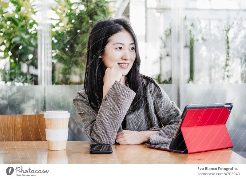 professional chinese entrepreneur woman working on laptop in cafeteria. Technology, lifestyle asian technology coffee tablet oriental business mobile phone