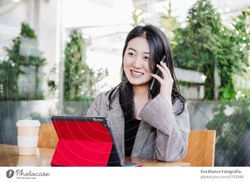 professional chinese entrepreneur woman working on mobile phone in cafeteria. Technology, lifestyle asian laptop technology coffee tablet oriental business