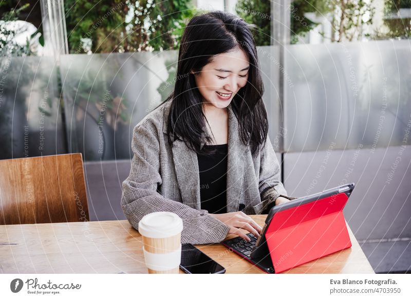 professional chinese entrepreneur woman working on laptop in cafeteria. Technology, lifestyle asian technology coffee tablet oriental business mobile phone