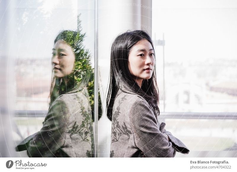 portrait of confident chinese business woman with arms crossed in office. Reflection on glass asian laptop technology cafe coffee cafeteria tablet oriental