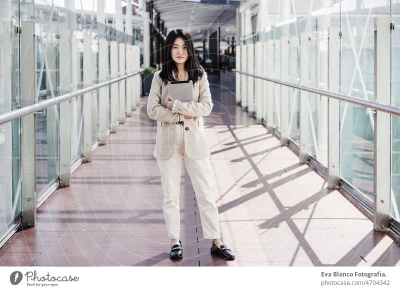 portrait of beautiful chinese business woman holding tablet in building office. Technology asian laptop technology cafe coffee cafeteria oriental mobile phone