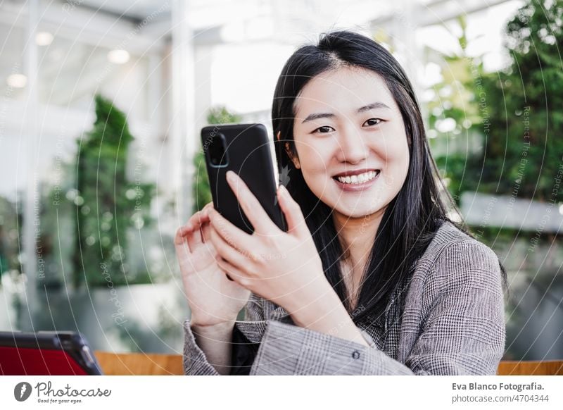 happy business woman in office using mobile phone and digital tablet. office and co working chinese asian laptop technology cafe coffee cafeteria oriental