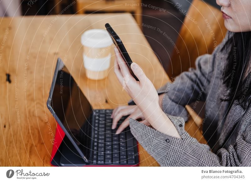 unrecognizable business woman working in digital tablet and mobile phone in office. technology chinese asian laptop cafe coffee cafeteria oriental cheerful