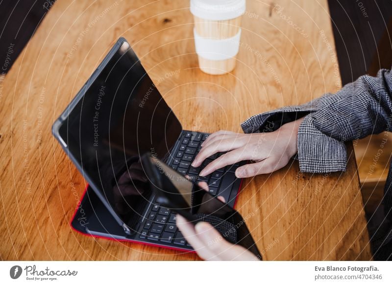 unrecognizable business woman working in digital tablet and mobile phone in office. technology chinese asian laptop cafe coffee cafeteria oriental cheerful