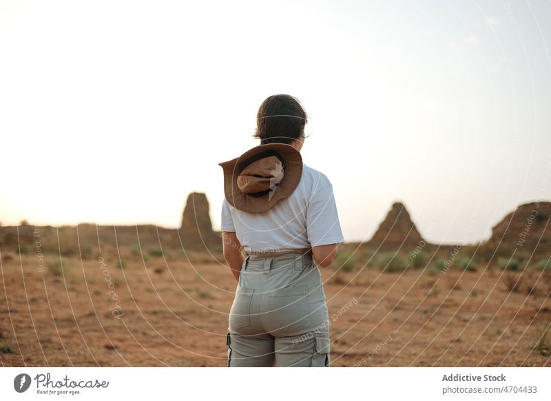 Anonymous traveler standing in desert field trip adventure arid journey explore barren drought vacation dry bush vegetation hat vegetate waterless tourism