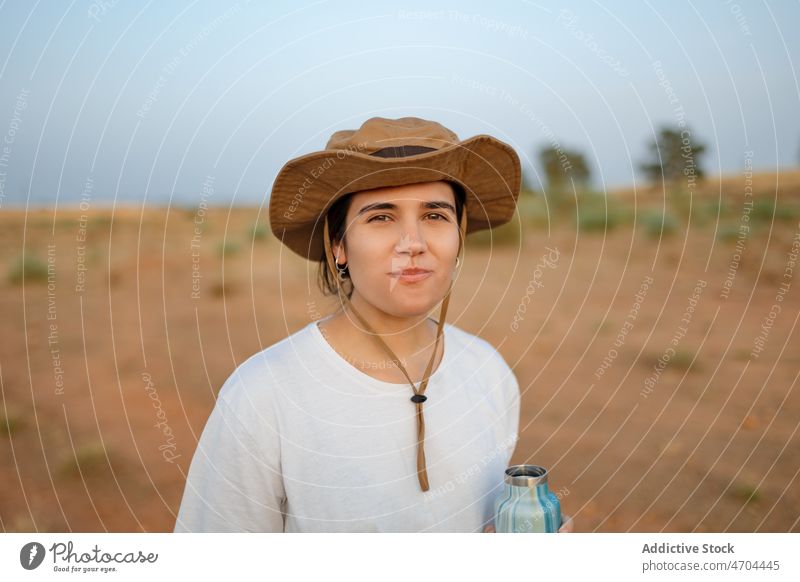 Woman drinking water in desert field woman traveler trip adventure journey thirst drought hydrate bottle explore barren dry bush vegetation vegetate waterless