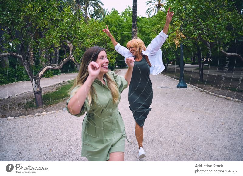 Positive women walking in park friendship bonding relationship spend time having fun enjoy pastime together city female tree girlfriend summer best friend glad