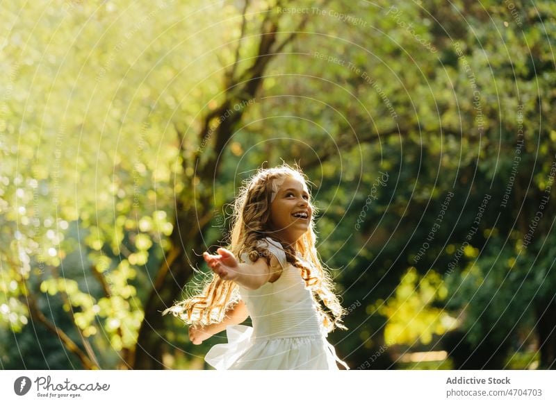 Happy girl dancing in park in First Communion dress catholic first communion religion holy communion summer nature female cheerful happy carefree joy smile