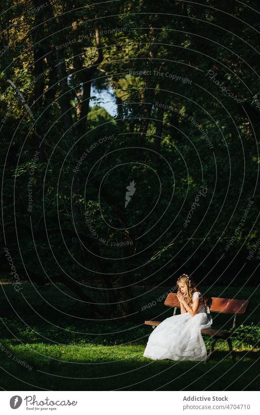 Young woman praying on bench in park religion first communion catholic holy communion summer female rest young music relax listen kid smile cheerful lifestyle