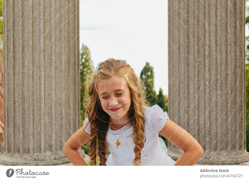 Charming girl in First Communion dress standing in park religion communion peaceful first communion catholic holy communion summer smile positive happy cheerful