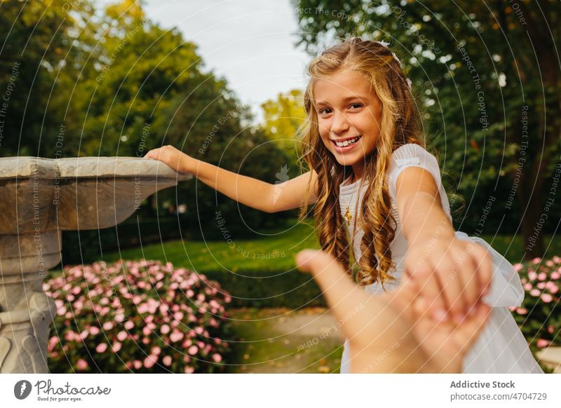 Happy girl in First Communion dress holding hands of father catholic communion religion first communion holy communion park happy cheerful smile summer joy