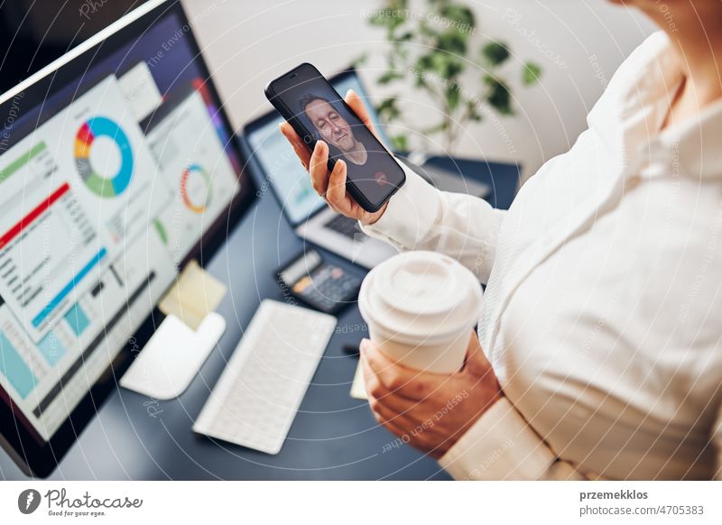 Businesswoman having video chat on mobile phone with her colleague. Businesswoman working with data on charts, graphs and diagrams on computer screen business