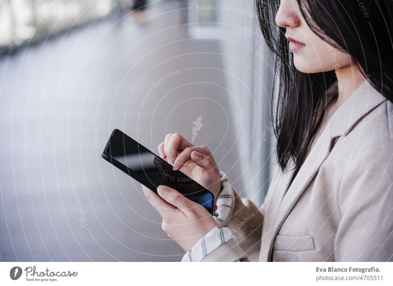 close up of chinese business woman using mobile phone in building office. Technology asian laptop technology cafe coffee cafeteria tablet cheerful young desk