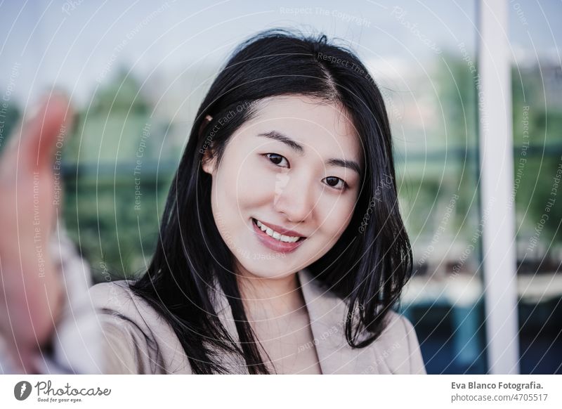 smiling beautiful chinese business woman using mobile phone in building office. taking selfie. Tech picture photographer asian laptop technology cafe coffee