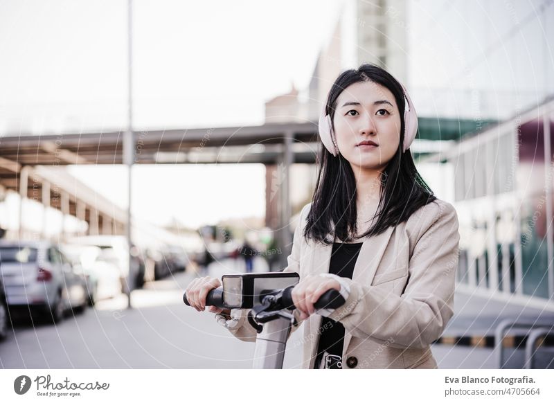 confident Businesswoman renting electric scooter in city. wearing headset. sustainable transport chinese headphones music urban modern sustainability