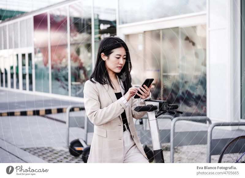 confident Businesswoman unlocking electric scooter through smart phone on road. sustainable transport chinese headphones music city urban modern sustainability