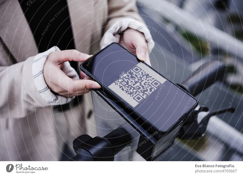 Businesswoman unlocking electric push scooter through smart phone on road. sustainable transport qr code unblocking unrecognizable touch wireless renting asian