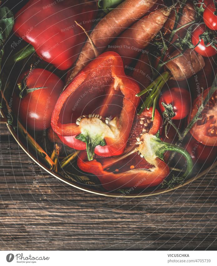 Close up of various raw red  vegetables in bowl at rustic table close up orange summer wooden halved bell pepper carrots tomatoes fresh healthy garden harvest