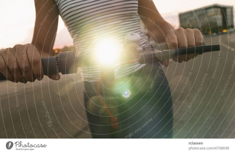 woman holds electric kick scooter or e-scooter with lamp at night in the city, Electric urban transportation concept image downtown sneakers light bike drive