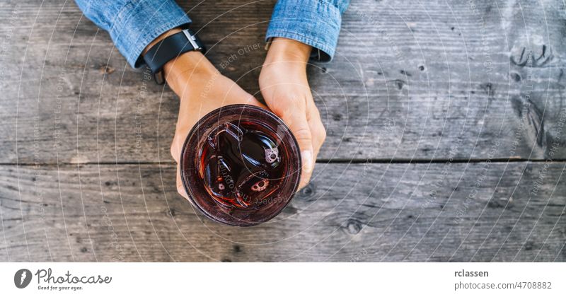 Woman holding glass of cocktail with ice on wooden background, top view shot, banner size hand bar drink infused juice mohito water alcohol aroma beverage