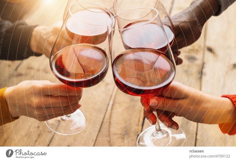 Hands toasting red wine glass and friends having fun cheering at winetasting experience - Young people enjoying time together at wine degustation - Youth and friendship concept