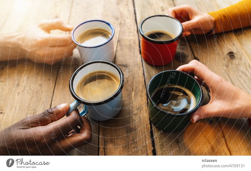 Friends group drinking cappuccino at coffee in a bar restaurant - People hands cheering and toasting - Social gathering concept with white and black men and women together