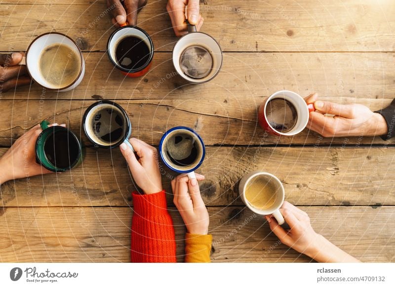 Friends group drinking coffee and cappuccino in a bar or restaurant - People hands cheering and toasting on top view point - breakfast together concept with white and black men and women