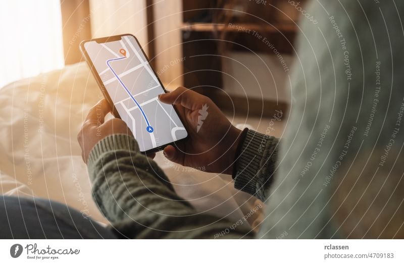 Tourist using GPS map navigation app on smartphone screen to get direction to destination address in the city at a hotel room, travel and technology concept image