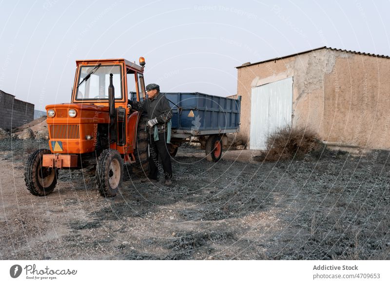 Old tractor farmer repairing detail in tractor cabin man work cart senior maintenance prepare male agriculture farmland transport worker vehicle manual aged