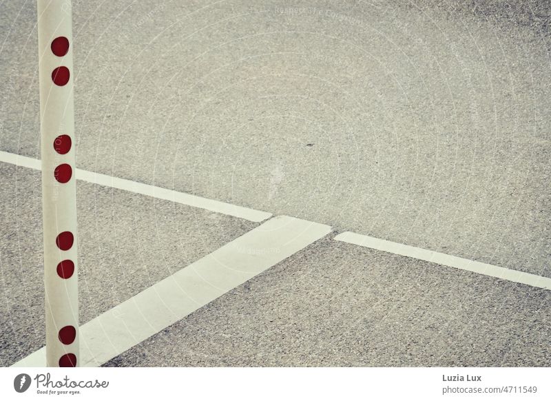 Parking markings in gray and white, in the foreground a barrier with dark red dots Gray White grey white Parking lot parking lot marking Control barrier points