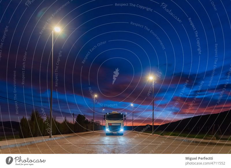 Truck with dangerous goods circulating at night under the light of street lamps on a street in an industrial estate. truck road streetlights traffic city drive