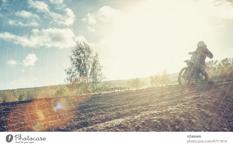 Enduro racer on dirt track on his Motocross MX cycle at sunset motocross extreme bike enduro rally dirtbike dust rider speed trail motor motorcycle action