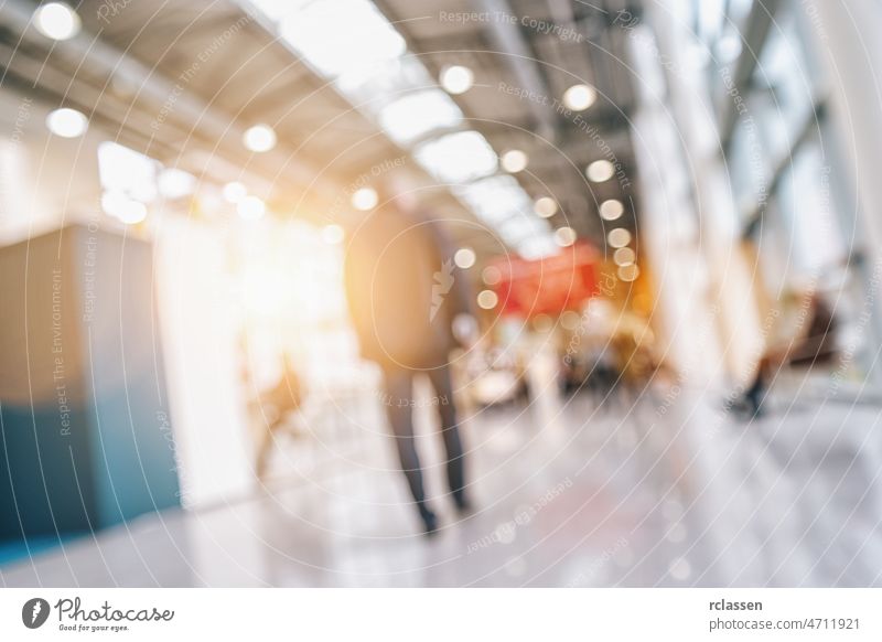 People walking on a trade show hall with booths, generic background with a blur effect applied crowd event exhibition expo fair blurred bokeh tradeshow business