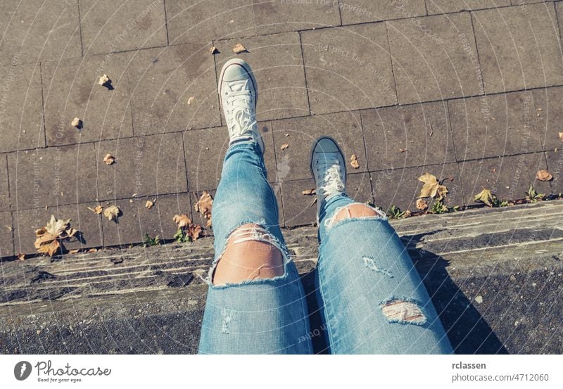 Young woman sit on a wall and swings her feets, personal pespective from above. pov people lifestyle point view way caucasian young first person view