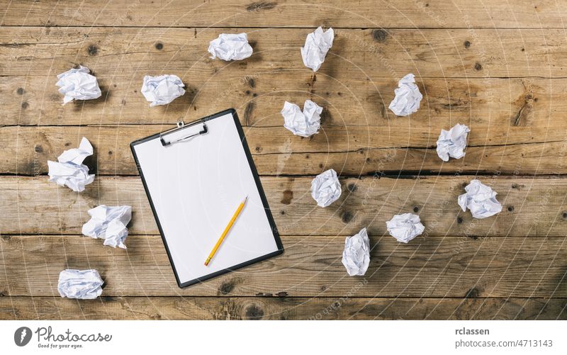 Clipboard with white sheet on wood background and Crumpled paper balls, with copyspace for your individual text. clipboard top view table thinking brainstorming