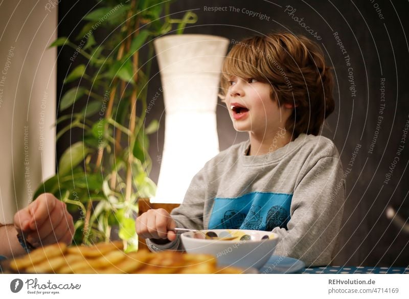 Child talks at dinner Dinner Eating conversation Schoolchild Dinner table Kitchen Food Nutrition Boy (child) Infancy portrait Table Bowl Spoon upbringing