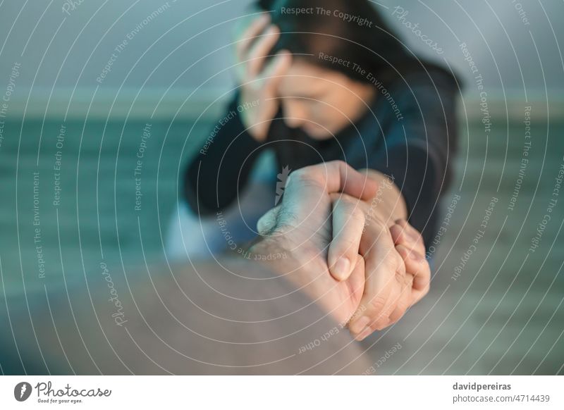 Unrecognizable woman with mental health problems receiving help from man holding her hand unrecognizable mental disorder helping hand concept therapy harassment