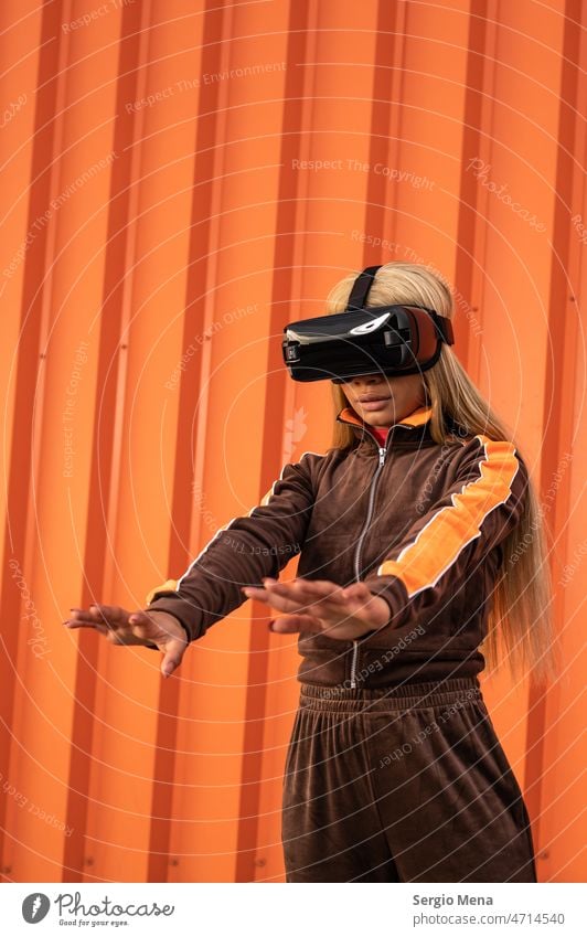 Cheerful African American woman with blonde hair wearing virtual reality goggles on an orange background one person afro american young sportswear lifestyle