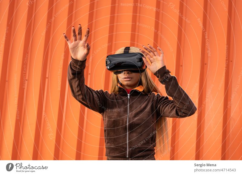 Cheerful African American woman with blonde hair wearing virtual reality goggles on an orange background one person afro american young sportswear lifestyle