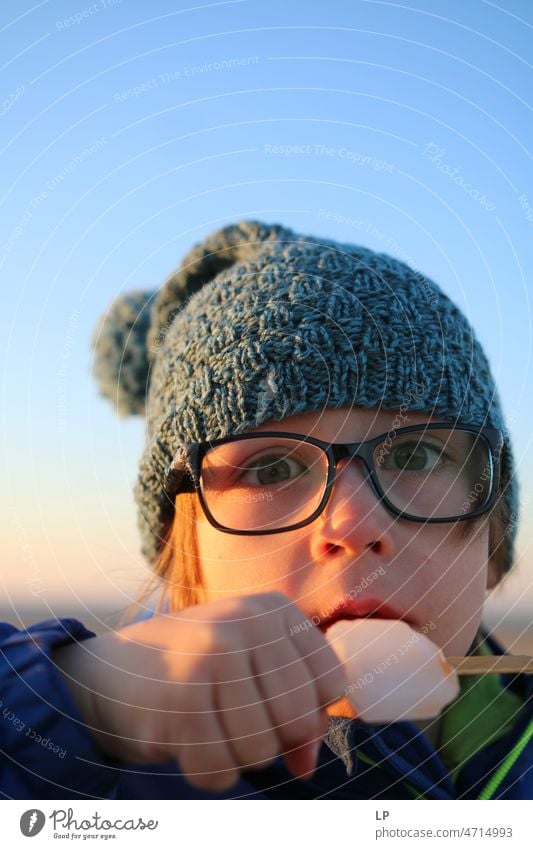 child wearing glasses looking curious at the camera and eating an icecream Emotions Mysterious Identity Uniqueness fortunate Freedom Happy Leisure and hobbies