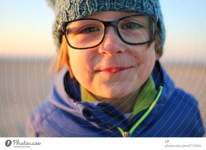 child wearing glasses looking curious at the camera and smiling Emotions Mysterious Identity Uniqueness Smiling face smilingly laughing child fortunate joyfully