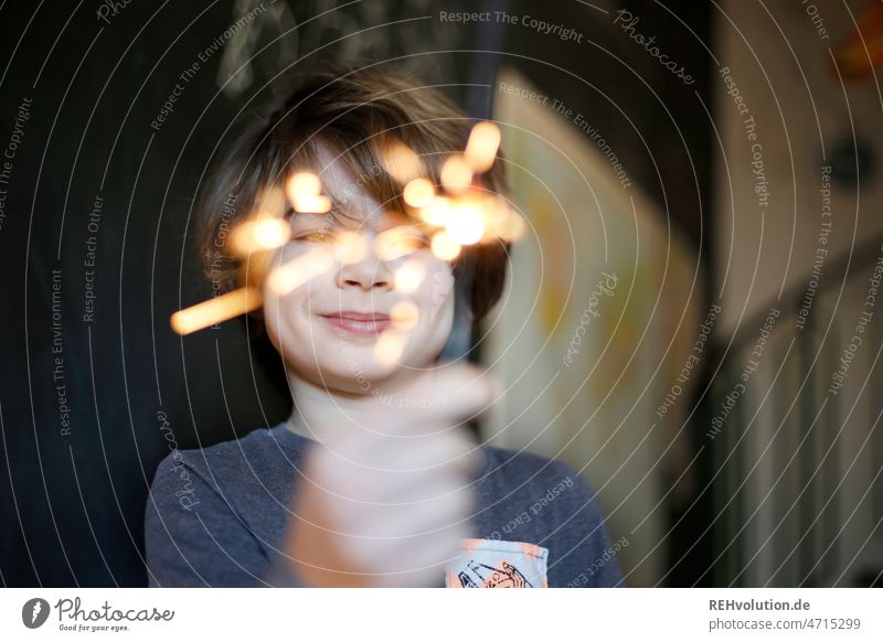 Child holding sparkler Boy (child) Infancy Sparkler Birthday Smiling contented Happy Positive Happiness Joy Face indoors carefree Cheerful Enchanting glad Cozy