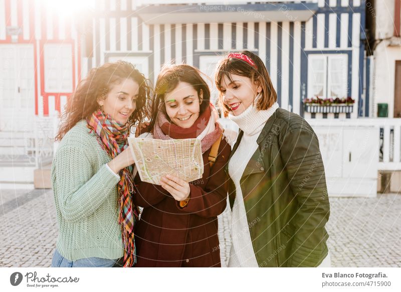 tourist female friends reading a map in in front of colorful houses.Costa Nova, Aveiro, Portugal women travel backpacker tourism caucasian friendship enjoy