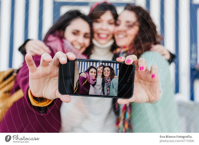 happy women friends using mobile phone in front of colorful houses.Costa Nova, Aveiro, Portugal woman travel tourist enjoy aveiro portugal costa nova tourism