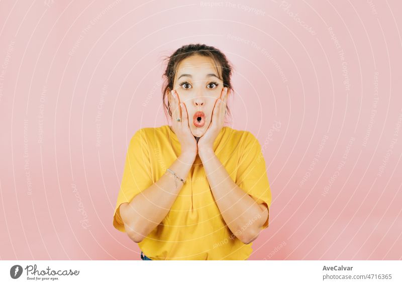 Young african woman funny expression hands on cheeks surprised, cute and modern posing isolated over pink color wall background. Daily expressions with copy space in studio.